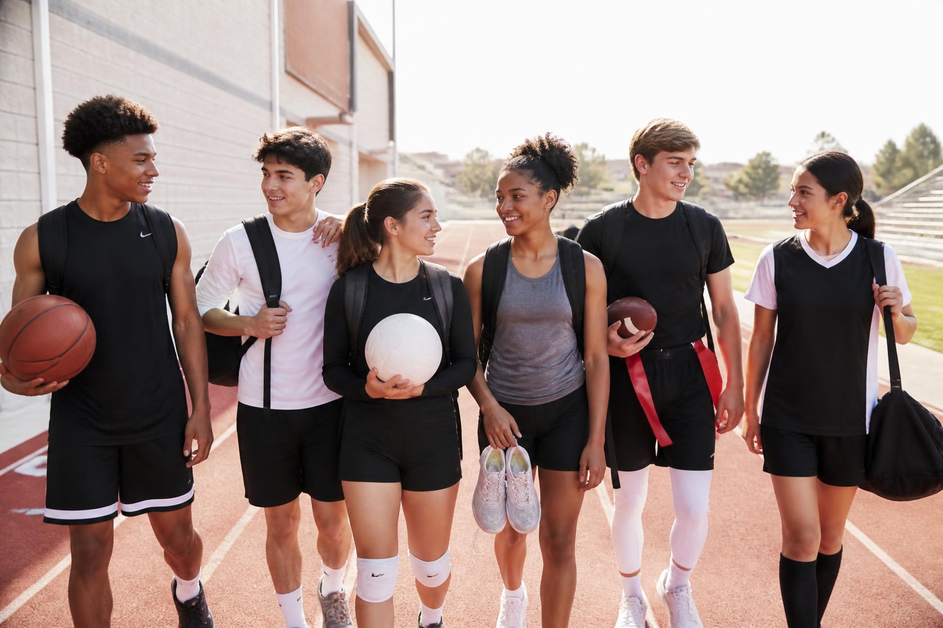 Teenage athletes from several sports walking and talking together after practice