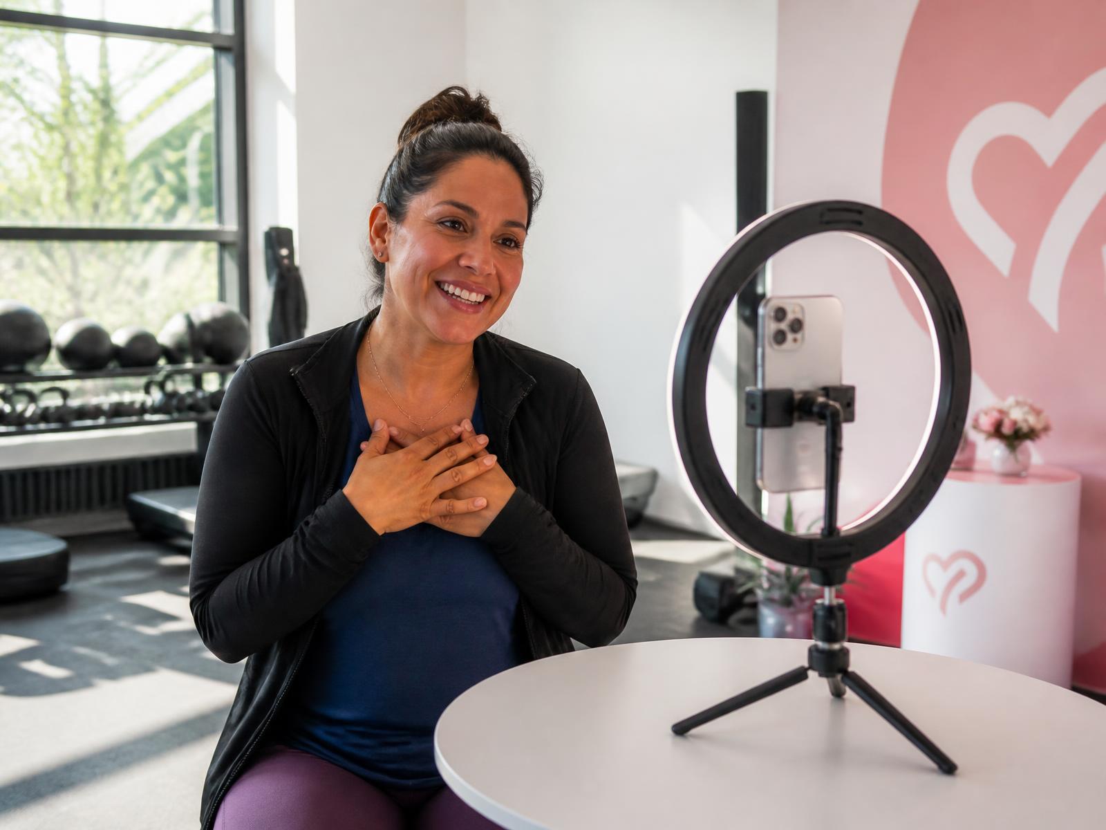 A parent recording a short video message at a branded recording station inside a bright gym