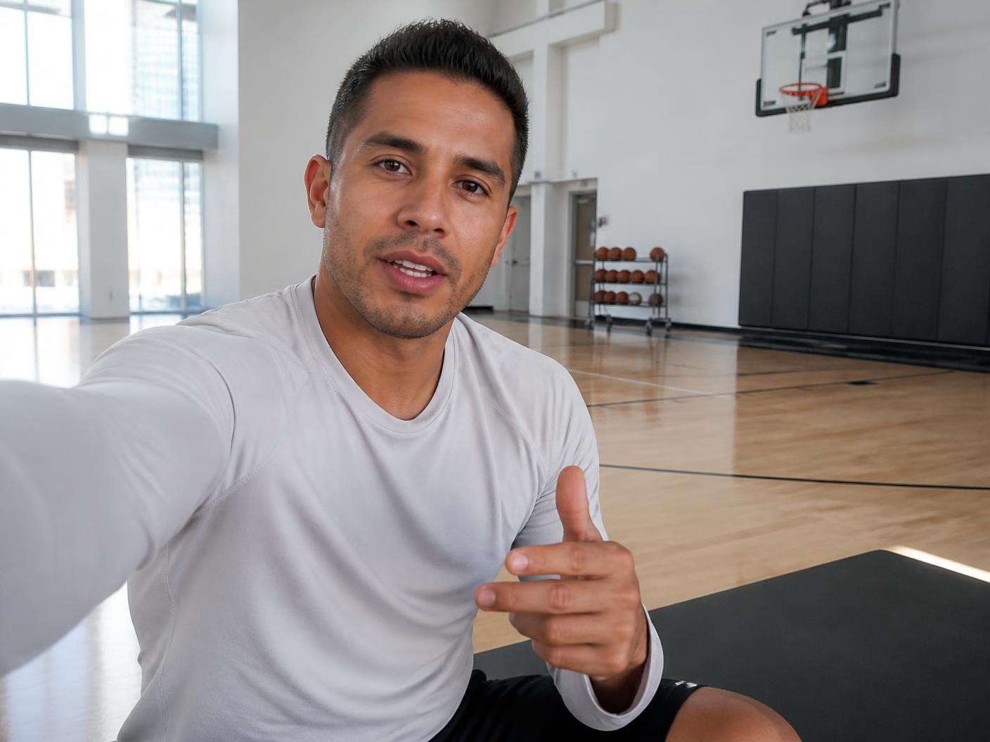 An accomplished athlete recording a short video message on his phone in a bright modern gym
